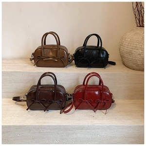 Detail view of four vintage leather bow handbags in red, black, brown, and coffee colors