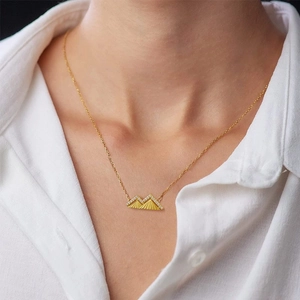Nahaufnahme einer goldenen Berg-Halskette mit weißen Zirkonia-Akzenten an einem Modell
