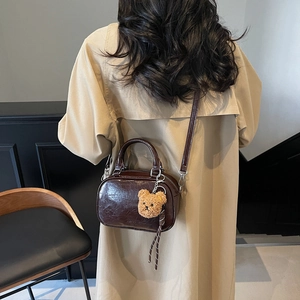 Vintage dark brown crossbody bag with glossy crackle texture and bear charm detail