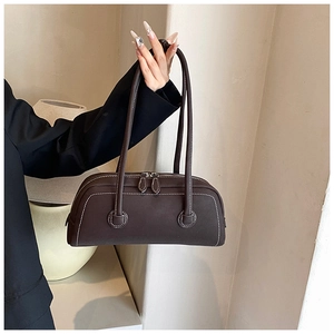 Detail of dark brown tote bag featuring white contrast stitching and dual zipper closure