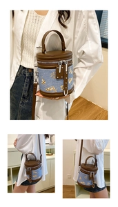 Détail du sac seau en denim bleu et cuir marron avec broderie florale dorée
