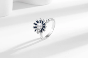 Detail of sunflower spinner ring with blue petals, pearl center and crystal butterfly