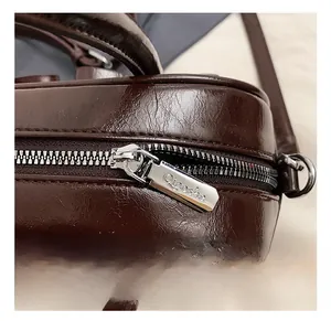 Macro shot of polished silver zipper detail and oily leather texture of the dark brown bag