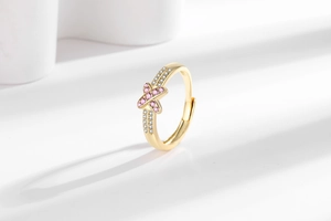 Macro shot of 18K gold plated X-shaped ring with pink and white zircon stones