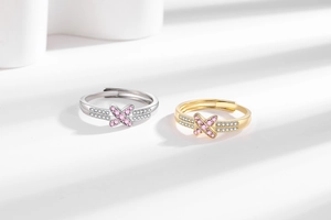 Detail of adjustable silver and gold rings with pink X-shaped zircon and white stones