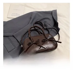 Detail of a dark coffee brown bowling bag with bow accents on a casual suit background