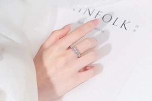 Close-up of silver ring with pink gemstone and cross pattern on a model finger