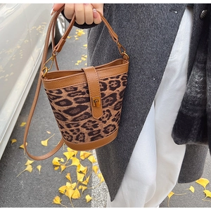 Close-up of leopard print bucket bag with gold lock and faux leather trim detail