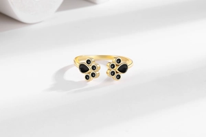 Detail of adjustable gold ring featuring cute black paw prints and polished finish