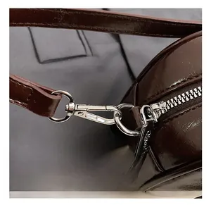 Detail view of the silver metal buckle and zipper on a dark brown leather shoulder bag