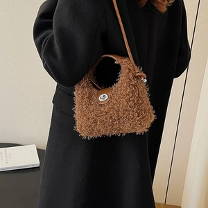 Sac à main en peluche marron avec poignée en cuir et fermoir en métal sur manteau noir