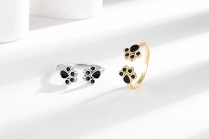 Detailed view of adjustable cat paw rings in gold and silver finish with black enamel