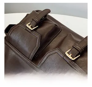 Close-up of deep brown leather tote bag showing dual pockets and precise stitching