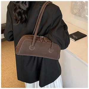 Detail view of coffee suede baguette bag with contrast stitching and double zippers