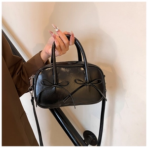 Close-up of black patent leather bowling bag with double bow details and glossy finish