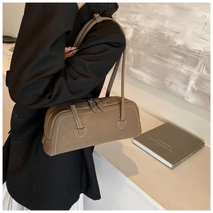 Detail of taupe leather tote bag with white stitching shown on shoulder