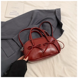 Detailed close-up of dark red vintage leather bag with bow accents and top handle