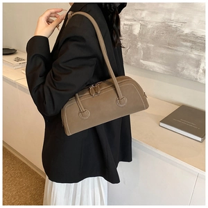 Close-up of a dark brown leather baguette bag with distinctive white contrast stitching