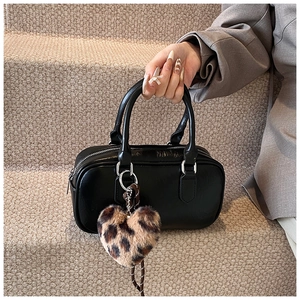 Detail of black faux leather bowling bag with leopard print plush heart charm and silver hardware