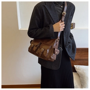Close-up of brown vintage leather tote bag with dual front pockets and adjustable strap