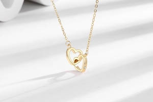 Detail of interlocking gold double heart necklace with a sparkling zircon accent