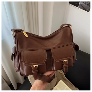 Detail of dark brown leather messenger bag featuring double buckled front pockets