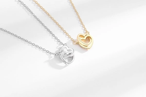 Close-up of interlocking gold and silver double heart pendants with zircon detailing