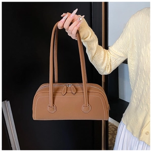 Detail view of brown tote bag featuring white contrast stitching and silver zippers