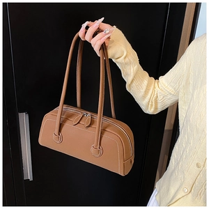Detail shot of brown cylinder leather tote bag with contrast white stitching and twin zippers