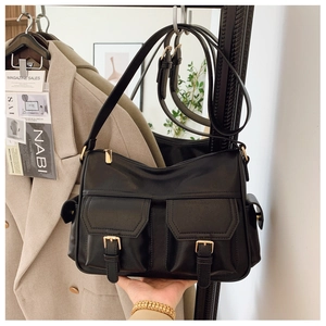 Detail of black utility tote bag with double gold buckle pockets and leather texture
