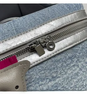 Dettaglio della cerniera in metallo argento e della trama denim blu sulla borsa