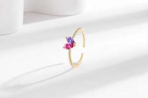 Detailed macro of gold open ring featuring interlocking pear-cut pink and purple stones