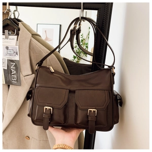 Detail of dark brown vintage faux leather tote with dual front pockets and gold metal buckles