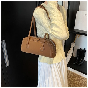 Detail of brown leather tote bag featuring white contrast stitching and slim shoulder straps
