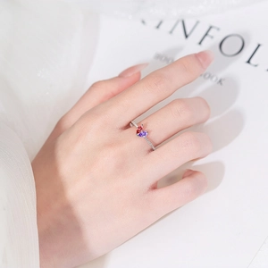 Silver beaded ring with red and purple heart crystals on a hand with lace background