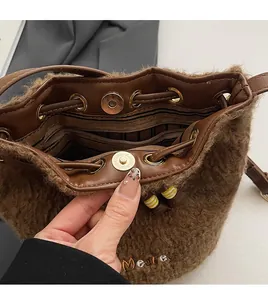 Detail view of winter brown plush bucket bag with golden magnetic buckle and logo