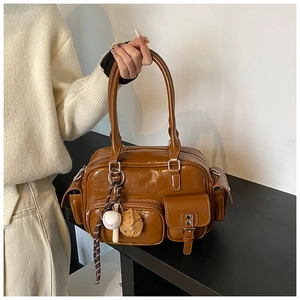 Detail of caramel brown faux leather tote bag with multi-pockets and baseball charm