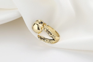 Macro shot of gold gothic skull and skeletal hand claw ring on white fabric