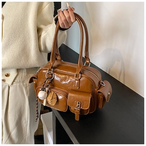 Detail of a brown glossy tote bag featuring multiple pockets and a baseball charm