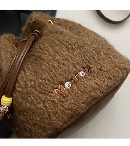 Detail of plush brown teddy fabric texture and Mooray embroidery on a bucket bag