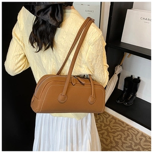 Close-up of caramel leather cylindrical tote bag with dual zippers and slim shoulder strap