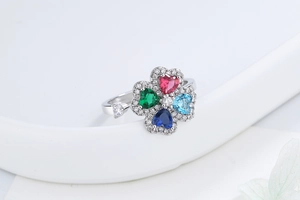 Macro detail of rotating four-leaf clover ring with multi-colored heart stones and micro-pave