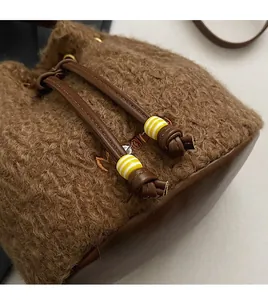 Close-up of brown wool bucket bag featuring leather base and striped bead drawstring detail