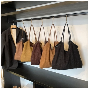 Vijf kleuren pluche tote bags hangend aan een rek voor herfst- en wintermode