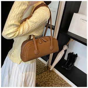 Macro view of brown leather tote bag with white contrast stitching and dual straps