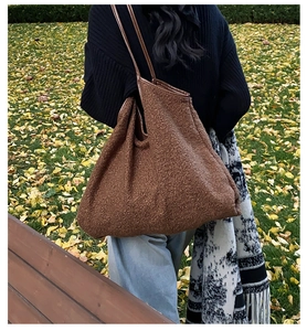 Detailed texture of brown faux shearling tote bag worn by model in an autumn park