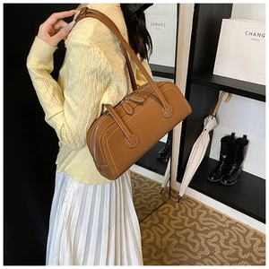 Detail view of brown leather tote bag with white contrast stitching and double handles