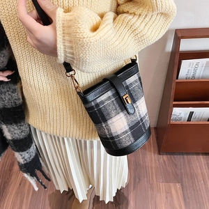 Retro plaid bucket bag with black leather straps and gold twist lock in a cozy room