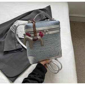 Dettaglio della piccola borsa squadrata in denim con bordo in PU argento e ciondolo a cavallo