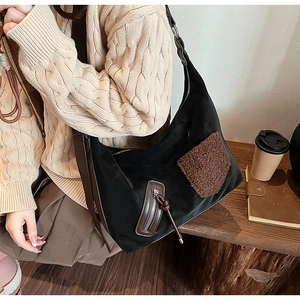 Close-up of black tote bag with brown shearling patch and wide shoulder strap